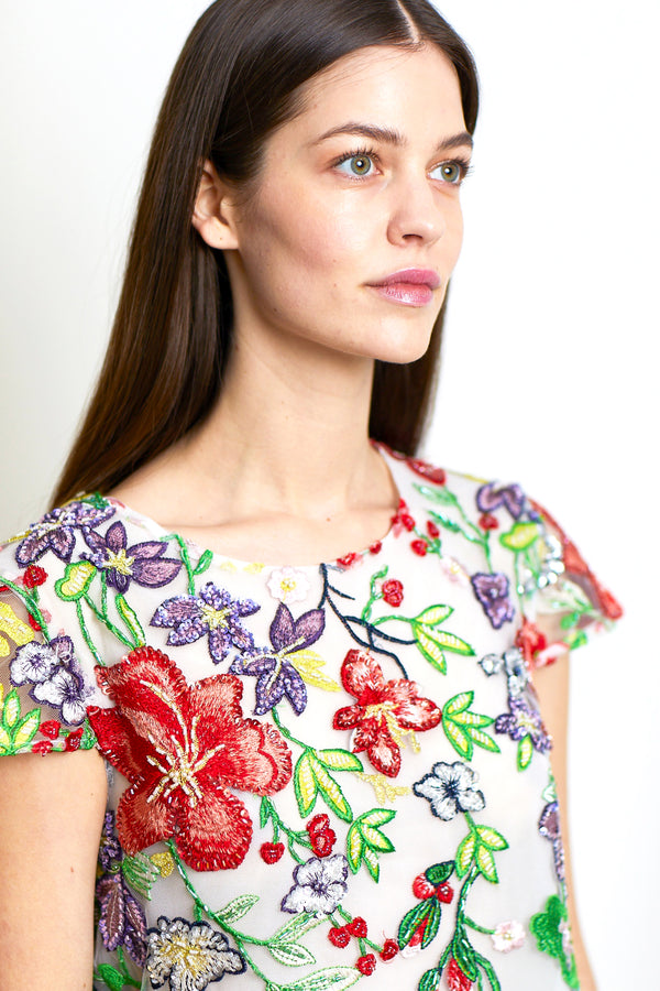 Model trägt handgearbeitetes Paillettentop in floralen Rot und Grüntönen